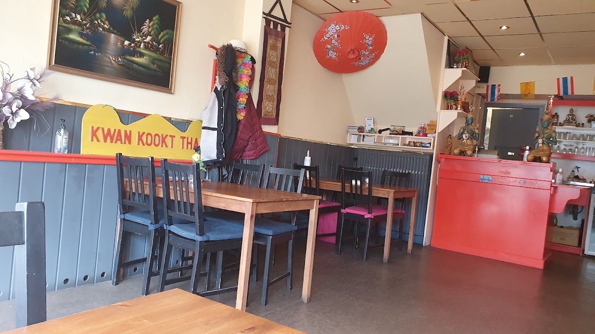 Het knusse interieur van Kwan kookt Thais met het bord 'Kwan kookt Thais' aan de muur